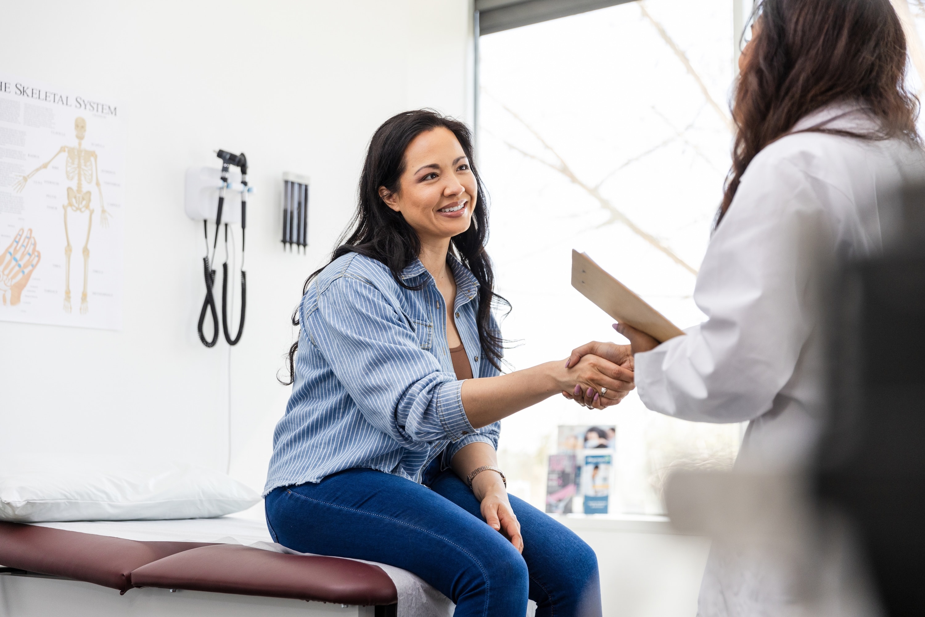 Mid adult female patient shakes hands with her doctor